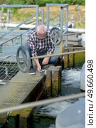 Man kneeling on lock gates. Стоковое фото, агентство Ingram Publishing / Фотобанк Лори