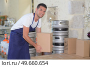 Man in cellar lifting cardboard box. Стоковое фото, агентство Ingram Publishing / Фотобанк Лори