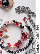 different   bracelets with black and red  semipreciouse stones with natural lava, shungite,  hematite,  rhodonite, coral  and chains.  top view. Стоковое фото, агентство Ingram Publishing / Фотобанк Лори