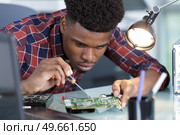 repairman disassembling smartphone with screwdriver. Стоковое фото, агентство Ingram Publishing / Фотобанк Лори