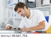 young repairman installing induction cooker in kitchen. Стоковое фото, агентство Ingram Publishing / Фотобанк Лори