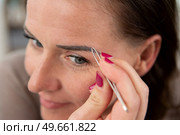 close up woman plucking her eyebrows with tweezers. Стоковое фото, агентство Ingram Publishing / Фотобанк Лори