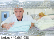 mature man working with towels in the rack. Стоковое фото, агентство Ingram Publishing / Фотобанк Лори