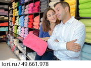 Woman trying to convince man to buy pink towel. Стоковое фото, агентство Ingram Publishing / Фотобанк Лори