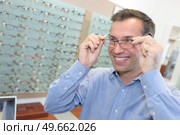 handsome young man trying pair of glasses. Стоковое фото, агентство Ingram Publishing / Фотобанк Лори