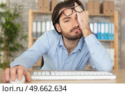 young bearded man sitting at desk looking sleepy. Стоковое фото, агентство Ingram Publishing / Фотобанк Лори