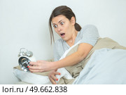 woman oversleeping and realising time on alarmclock. Стоковое фото, агентство Ingram Publishing / Фотобанк Лори