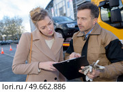 woman looking at paperwork held by breakdown recovery driver. Стоковое фото, агентство Ingram Publishing / Фотобанк Лори