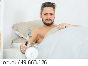 sleepy young man breaking alarm with a hammer. Стоковое фото, агентство Ingram Publishing / Фотобанк Лори