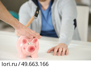 hand stopping person from breaking piggybank with hammer. Стоковое фото, агентство Ingram Publishing / Фотобанк Лори