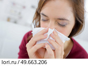burnette woman blowing nose into tissue. Стоковое фото, агентство Ingram Publishing / Фотобанк Лори