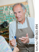 Shopkeeper holding out key duplicates to his client. Стоковое фото, агентство Ingram Publishing / Фотобанк Лори