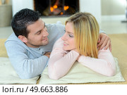Couple layed in front of log fire. Стоковое фото, агентство Ingram Publishing / Фотобанк Лори