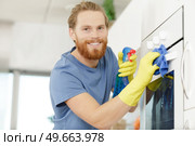 happy young man cleaning oven. Стоковое фото, агентство Ingram Publishing / Фотобанк Лори