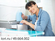 happy woman pouring fabric softener into washing machine. Стоковое фото, агентство Ingram Publishing / Фотобанк Лори