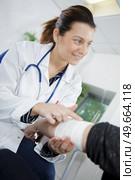 portrait of woman doctor bandaging hand. Стоковое фото, агентство Ingram Publishing / Фотобанк Лори