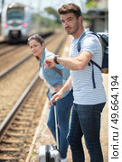 man checking the time on wristwatch at rail station platform. Стоковое фото, агентство Ingram Publishing / Фотобанк Лори