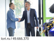 male customer shaking hands with motorbike salon manager. Стоковое фото, агентство Ingram Publishing / Фотобанк Лори