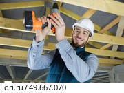 man drills the wooden ceiling plank. Стоковое фото, агентство Ingram Publishing / Фотобанк Лори