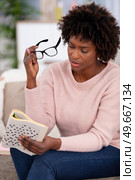 smiling pretty young woman doing crosswords. Стоковое фото, агентство Ingram Publishing / Фотобанк Лори