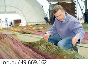 a fisherman is untangling nets. Стоковое фото, агентство Ingram Publishing / Фотобанк Лори