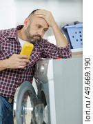 depressed serviceman working on washing machine. Стоковое фото, агентство Ingram Publishing / Фотобанк Лори