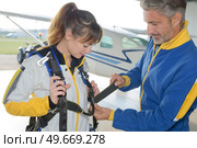 instructor fastening harness on female parachutist. Стоковое фото, агентство Ingram Publishing / Фотобанк Лори