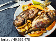 Appetizing river carp baked with fruits. Grilled fish. Baked carp with fruit, seafood. Стоковое фото, агентство Ingram Publishing / Фотобанк Лори
