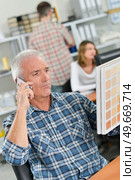 Man looking at page of color samples, on telephone. Стоковое фото, агентство Ingram Publishing / Фотобанк Лори
