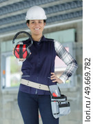 young female builder in  helmet showing earmuff. Стоковое фото, агентство Ingram Publishing / Фотобанк Лори