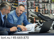 mechanic and smiling customer chatting about motorbike. Стоковое фото, агентство Ingram Publishing / Фотобанк Лори