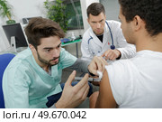 young internist doctor injecting a patient under surveillance. Стоковое фото, агентство Ingram Publishing / Фотобанк Лори
