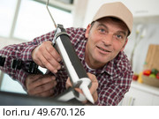 young repairman working at the kitchen with glue gun. Стоковое фото, агентство Ingram Publishing / Фотобанк Лори