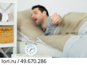 man stretching in bed alarmclock in foreground. Стоковое фото, агентство Ingram Publishing / Фотобанк Лори