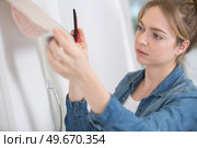 a young woman applying a roll of adhesive material. Стоковое фото, агентство Ingram Publishing / Фотобанк Лори