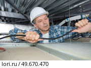 man fixing wires on the ceiling. Стоковое фото, агентство Ingram Publishing / Фотобанк Лори