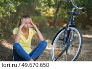 woman sitting on the soil next to a bike. Стоковое фото, агентство Ingram Publishing / Фотобанк Лори