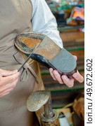 Cobbler scraping sole of shoe with a knife. Стоковое фото, агентство Ingram Publishing / Фотобанк Лори