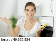 positive young blonde housewife doing oven clean-up in domestic kitchen. Стоковое фото, агентство Ingram Publishing / Фотобанк Лори