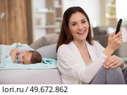 mum uses the phone while the baby sleeps. Стоковое фото, агентство Ingram Publishing / Фотобанк Лори