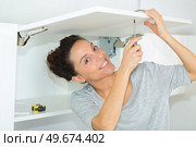 woman fixing a cabinet door. Стоковое фото, агентство Ingram Publishing / Фотобанк Лори