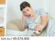woman in bed looking at alarm clock with shocked expression. Стоковое фото, агентство Ingram Publishing / Фотобанк Лори