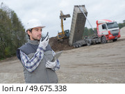 Man on construction site talking into walkie talkie. Стоковое фото, агентство Ingram Publishing / Фотобанк Лори