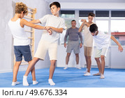 Diligent preteen student practicing self-defense techniques in pairs. Стоковое фото, фотограф Яков Филимонов / Фотобанк Лори
