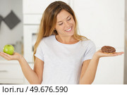 young blond woman is holding an apple and a donut. Стоковое фото, агентство Ingram Publishing / Фотобанк Лори
