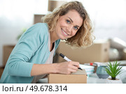 attractive woman signing on delivery paper. Стоковое фото, агентство Ingram Publishing / Фотобанк Лори