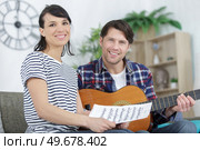 man plays guitar and woman holds sheet music. Стоковое фото, агентство Ingram Publishing / Фотобанк Лори