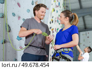 instructor securing a climbers rope by indoor wall. Стоковое фото, агентство Ingram Publishing / Фотобанк Лори