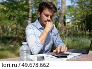 young businessman calculates finances outdoors. Стоковое фото, агентство Ingram Publishing / Фотобанк Лори