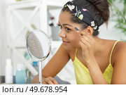 young woman using tweezers to pluck her eyebrows. Стоковое фото, агентство Ingram Publishing / Фотобанк Лори